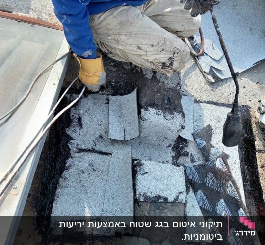 עובד עם מבער גז ואספלט לאיטום גג